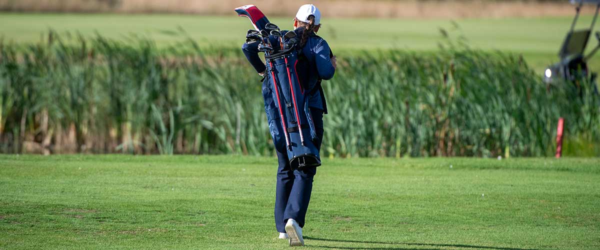 Pelaaja kävelemässä golf kentällä, bägi selässä. Kuvituskuva.